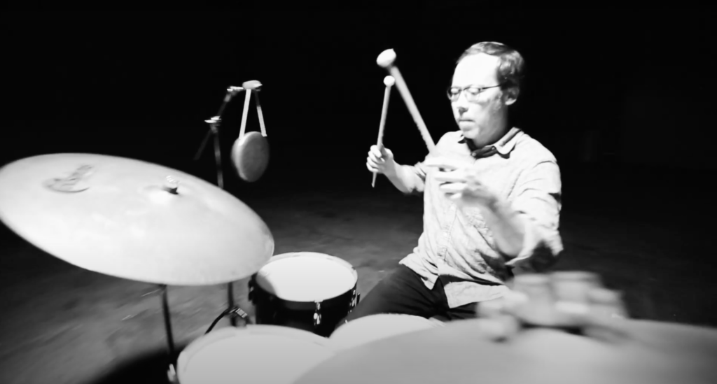 man playing drums in black and white