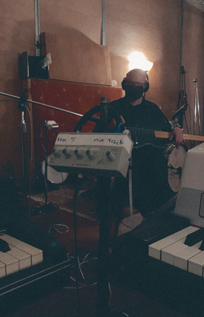man with bass guitar in a dark studio surrounded by equipment