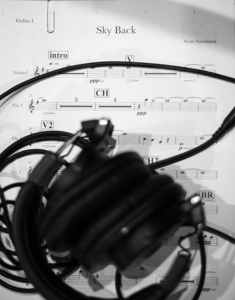 black and white image of sheet music for strings with headphones on top