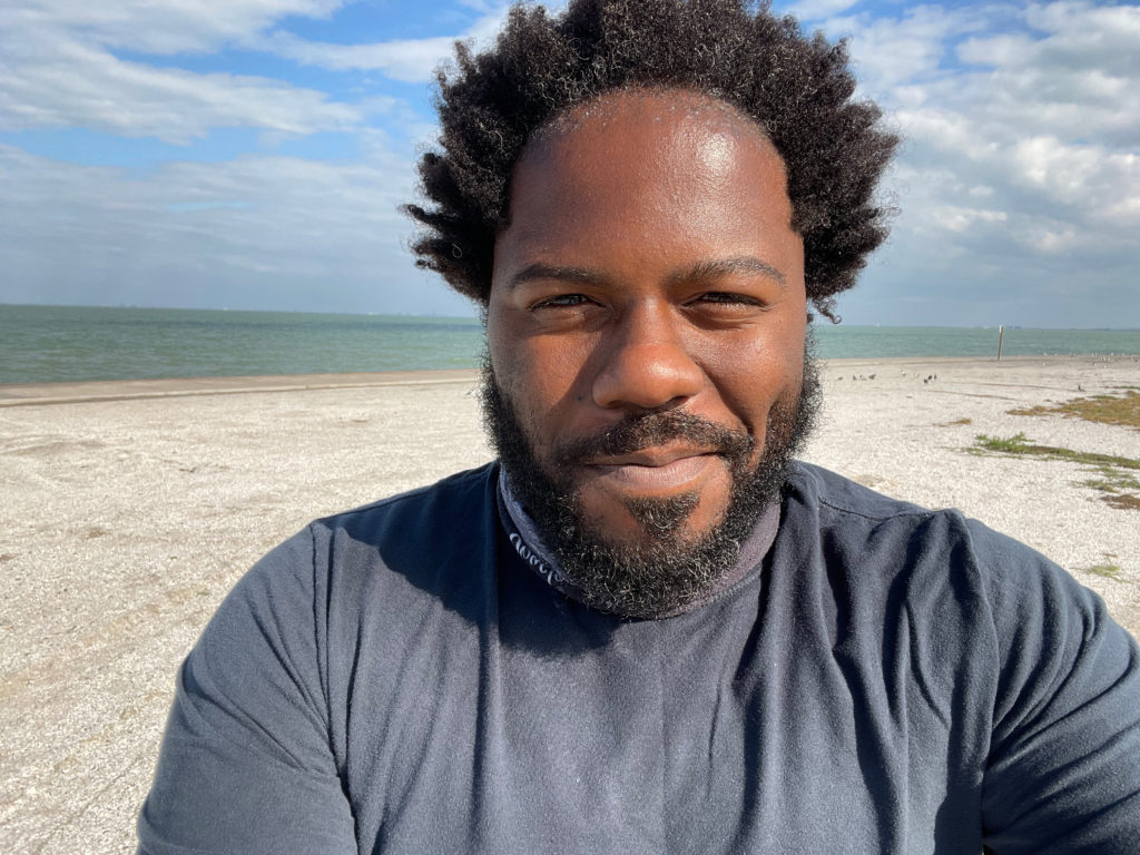 Portrait of a smiling black man with beach and ocean waves in the background