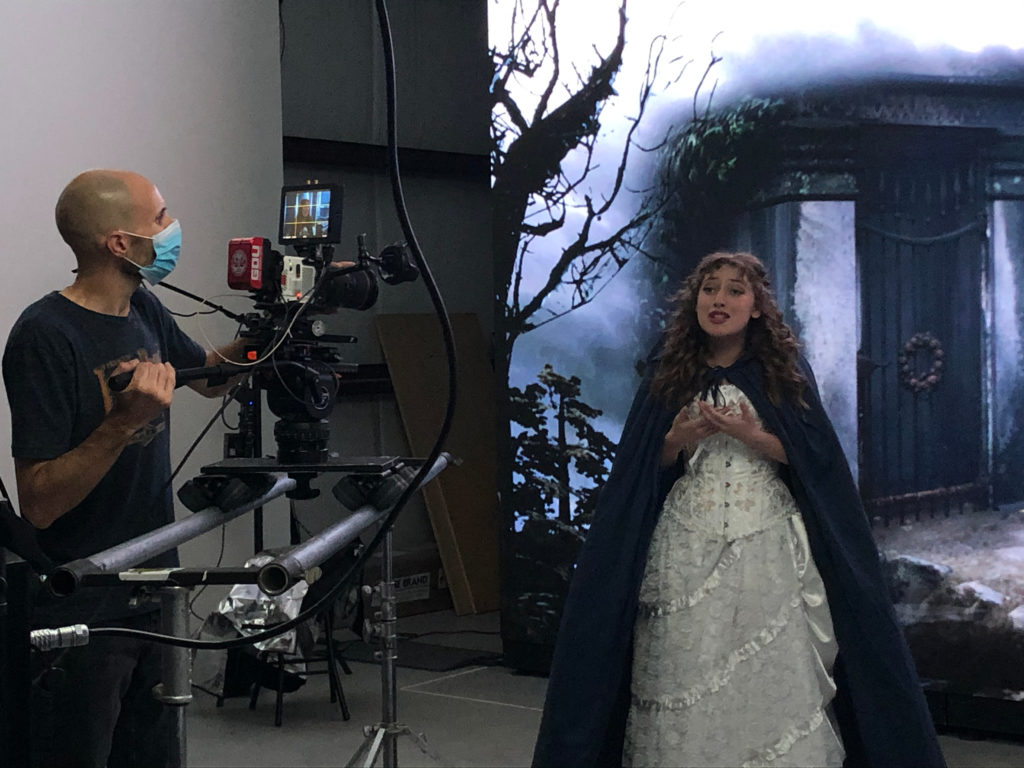 A student films a solo in costume in front of a digital background
