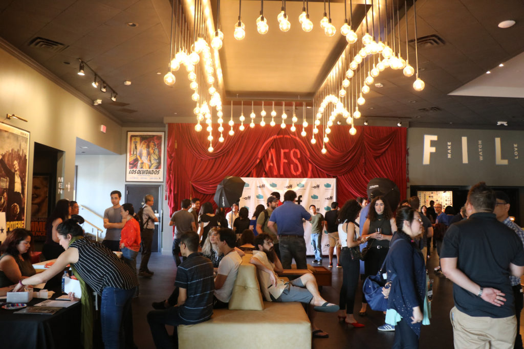 patrons in a low-lit theatre lobby anticipating a film event