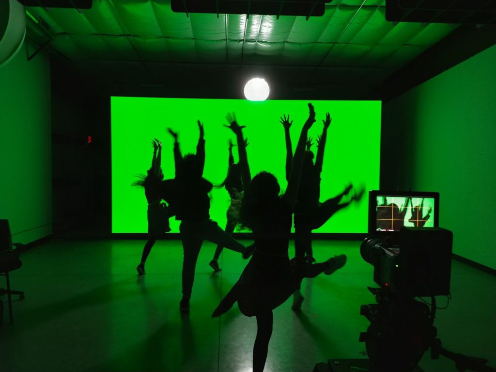 a group dancing in silhouette against a bright green background