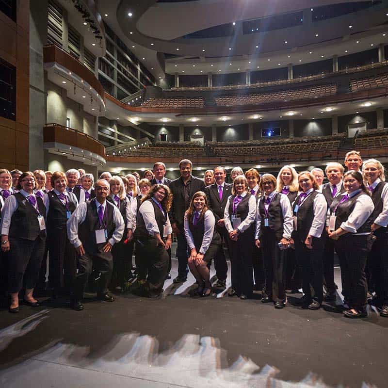 a group of Long Center volunteers post for a group picture onstage with Neil deGrasse Tyson after a show
