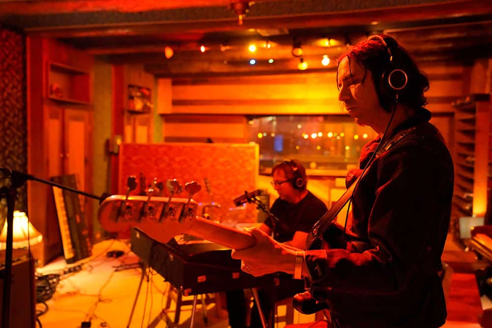 David Garza plays guitar in his studio, washed in orange light