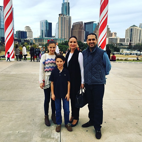 The Patino family poses for a photo on the Long Center's H-E-B Terrace with the skyline and candy-cane columns in the background
