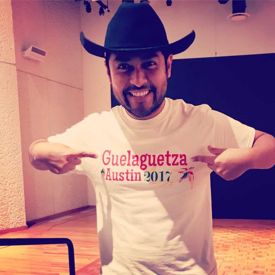 Edgar poses in a cowboy hat, pointing at his shirt that says "Guelaguetza Austin 2017"